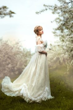 a woman wearing a white dress standing in the grass