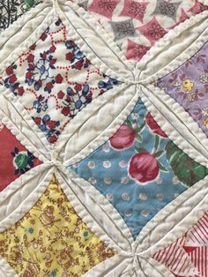 a close up of a quilt with many different colors and designs on it, including red, white, blue, green, yellow and pink