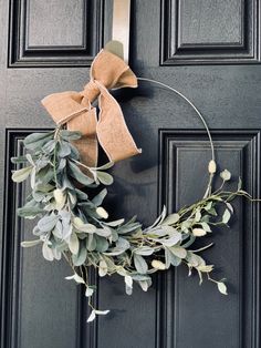 a wreath is hanging on the front door with a bow and greenery around it