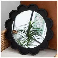 a round mirror sitting on top of a table next to a potted palm tree