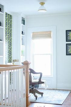 an empty room with a chair, desk and bookshelf on the wall in front of a window