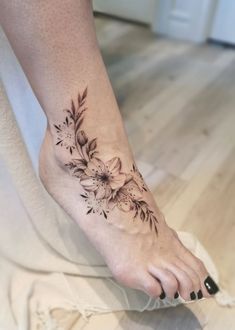 a woman's foot with a flower tattoo on the left side of her leg