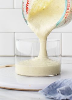 a person pouring batter into a glass on top of a counter