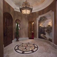 a foyer with a painting on the wall and a chandelier hanging from the ceiling