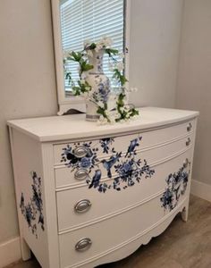 a white dresser with blue flowers painted on it