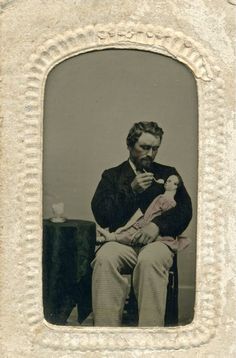 an old black and white photo of a man sitting in a chair holding a cat