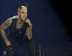 a man with horns on his head singing into a microphone