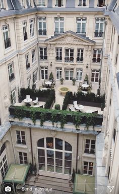 an aerial view of a building with tables and chairs in the courtyard, looking down