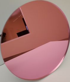 a round mirror reflecting a room with pink walls