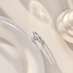 a diamond engagement ring sitting on top of a white plate next to a seashell