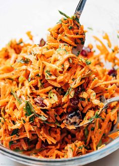 a bowl filled with shredded carrots and cranberries