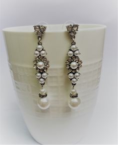 Elegant Vintage style Bridal Earrings. Made with clear crystals and crystal white pearls. They are about 21/4 inches long. Sparkling deco drama that makes a statement for brides or black tie affairs. Bright withe pearls and crystal against antique silver metal gives these earrings a beautiful pup out look. If you have any questions feel free to contact me via Etsy convo. Happy shopping with Simply Chic. Jeweled Metal Crystal Earrings For Wedding, Wedding Crystal Pearl Drop Earrings, Metal Dangle Crystal Earrings For Wedding, Dangle Crystal Earrings For Wedding, Silver Jeweled Pearl Earrings, Silver Pearl Earrings With Jeweled Details, Jeweled Dangle Bridal Earrings, Jeweled Silver Pearl Drop Earrings, Pearl Drop Metal Earrings For Wedding