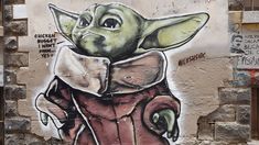 graffiti on the side of a building with an image of a baby yoda