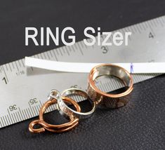 two rings sitting on top of a measuring tape with the words ring sizer above them