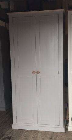 two white cupboards in a room with wood flooring