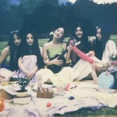 a group of young women sitting on top of a grass covered field next to each other