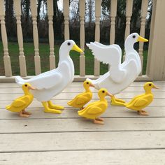 three plastic ducks and one duckling on a porch