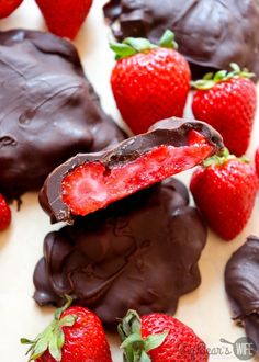 chocolate covered strawberries and strawberrys on a white surface with one broken in half