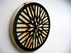 a clock made out of wood and metal on a white wall with black trimmings