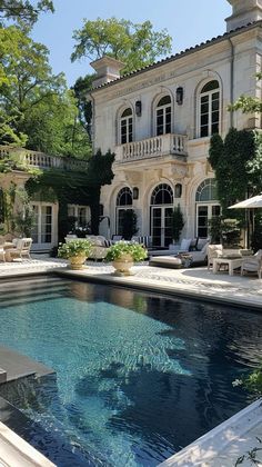 an outdoor swimming pool in front of a large house