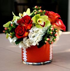 an arrangement of flowers in a football themed vase on a table with white and red roses