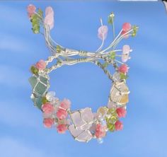 a close up of a bracelet made out of glass beads and flowers on a blue sky background