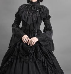 Step into a world of gothic elegance with our Black Gothic Lolita Ball Gown. This Victorian-inspired dress, adorned with layered tulle ruffles, is perfect for those seeking a dramatic and sophisticated look. Luxurious Black Fabric: Made from rich black fabric with intricate lace detailing, this gown exudes timeless gothic charm, ideal for formal events and themed occasions. Victorian-Inspired Design: The fitted bodice features exquisite lace patterns and a high collar, enhancing your silhouette Gothic Vampire Dress Victorian, 18th Century Gothic Fashion, Victorian Gothic Gown, Diy Victorian Dress, Goth Quinceanera Dress, Victorian Goth Clothes, Victorian Dress Design, Victorian Gothic Aesthetic Outfit, Dark Victorian Dress