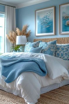 a bedroom with blue walls and white bedding in front of a large window that looks out onto the ocean