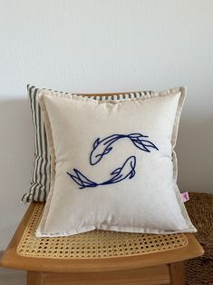 a white pillow sitting on top of a wooden chair next to a black and white striped pillow