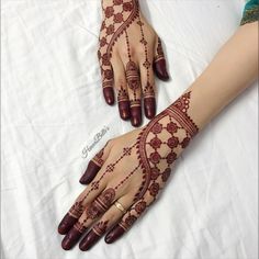 two hands with henna designs on them sitting on a white sheet covered tablecloth