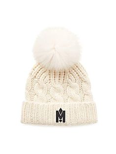 a white hat with a pom - pom on the top and a black m logo