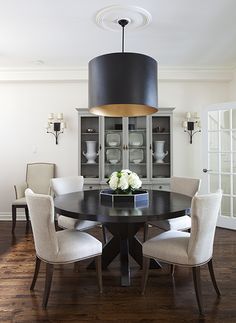 the dining room table is surrounded by white chairs and a black chandelier over it