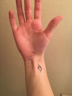 a person's hand with a small tattoo on the middle of their left wrist