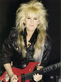 a woman with blonde hair holding a red guitar