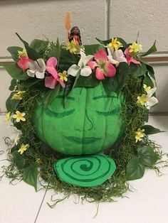 a green planter with flowers in it sitting on the ground