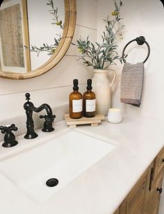 a white sink sitting under a mirror next to a faucet and soap dispenser