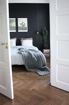 an open door leading to a bedroom with black walls and white bed linens on the bed