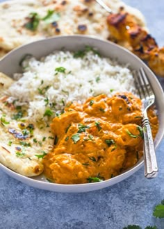 a white bowl filled with rice and chicken next to flat bread on a blue surface