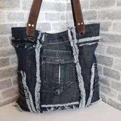 a bag made out of old jeans with leather handles and zippers on the front