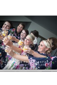 a group of women standing next to each other holding wine glasses in their hands and smiling at the camera