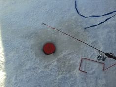 an overhead view of a fishing rod and reel in the snow with a red box attached to it