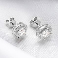 Experience the timeless elegance of a Classic 2.0 Carat Round Cut Moissanite Stud Earrings from Evani Naomi Jewelry. These high-quality earrings are simply stunning in their design and craftsmanship. Their brilliant shine is much like that of a mined diamond but comes at a significantly more affordable price. Each stud is finely handcrafted to last a lifetime, offering you a timeless piece to enjoy for years to come. They are made from a blend of 92.5% pure silver + 7.5% hypoallergenic metals an Timeless Diamond White Cubic Zirconia Bridal Earrings, Timeless Cluster Earrings With Brilliant Cut Cubic Zirconia, Timeless Bridal Earrings In Diamond White Cubic Zirconia, Elegant Round Cluster Earrings With Lab Grown Diamonds, Timeless Cubic Zirconia Bridal Earrings For Anniversary, Timeless Diamond White Round Bridal Earrings, Timeless Diamond White Bridal Earrings, Timeless Formal Diamond Earrings With Halo, Timeless Formal Diamond Earrings With Halo Detail