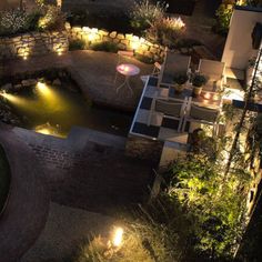 an aerial view of a backyard at night with lights on the patio and pool area