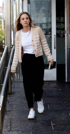 a woman is walking down the sidewalk with her hand in her pocket