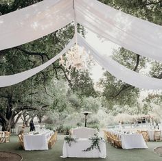 an outdoor wedding setup with white linens and greenery