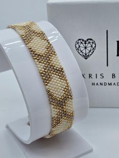 a white bracelet with gold beads on it and a box for the bracelet is next to it