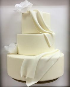 a three tiered cake with white icing and flowers