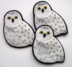 three white owls with yellow eyes sitting on top of each other in front of a white background