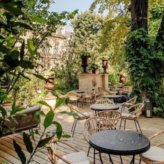 an outdoor dining area with tables and chairs on a wooden deck surrounded by greenery