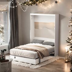 a white bed sitting in a bedroom next to a christmas tree